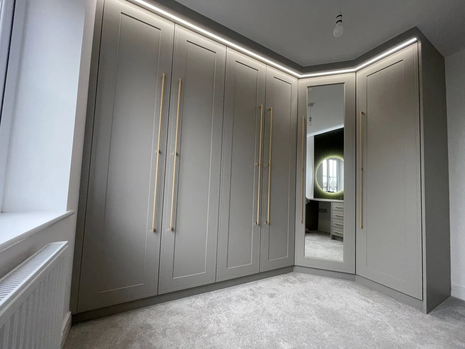Floor-to-ceiling grey wardrobes with a mirrored corner and LED lighting