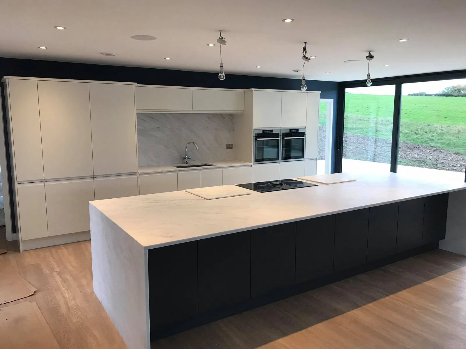 Handleless light-grey kitchen with a black island and garden doors