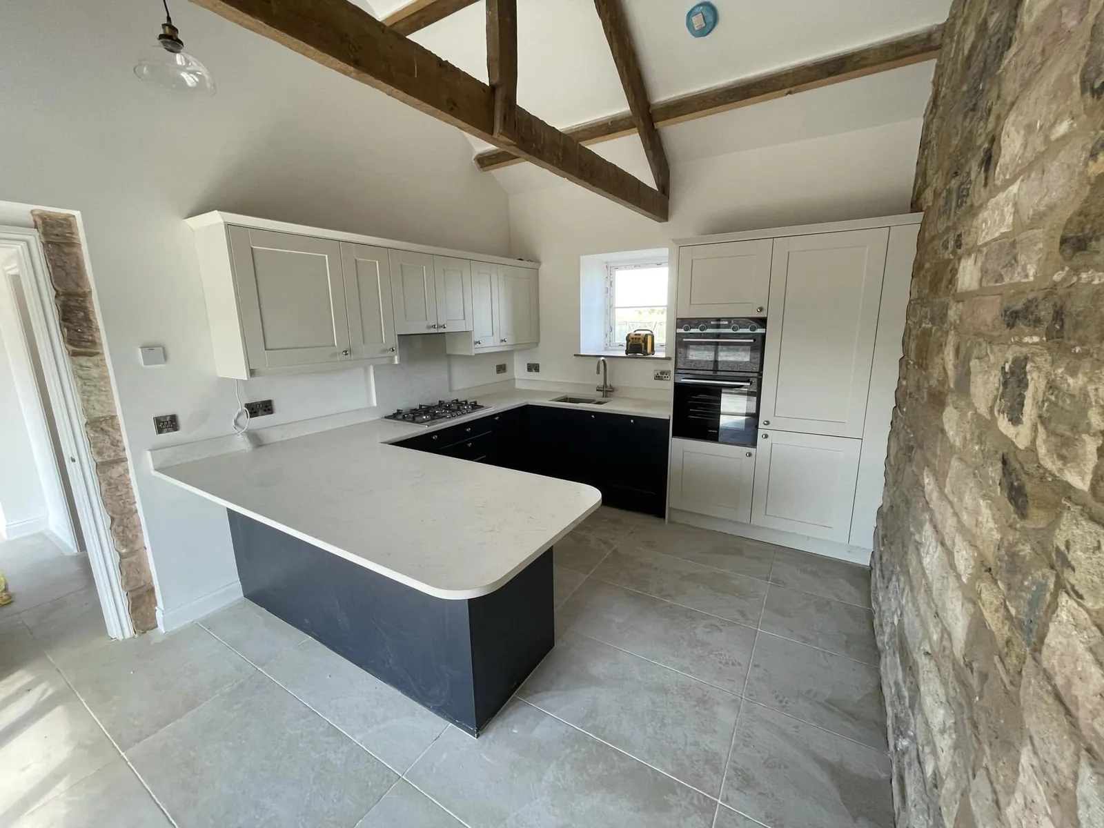 White and charcoal kitchen with an island beside a stone feature wall