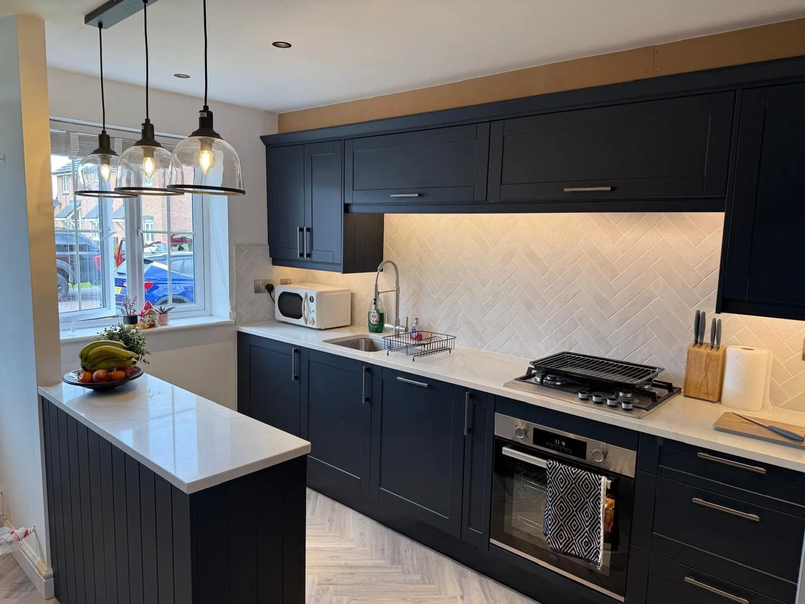 Dark blue fitted kitchen with marble-effect splashback and worktops