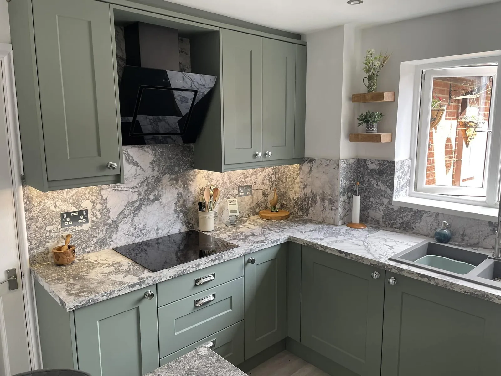 Sage green corner kitchen with marble-effect worktops
