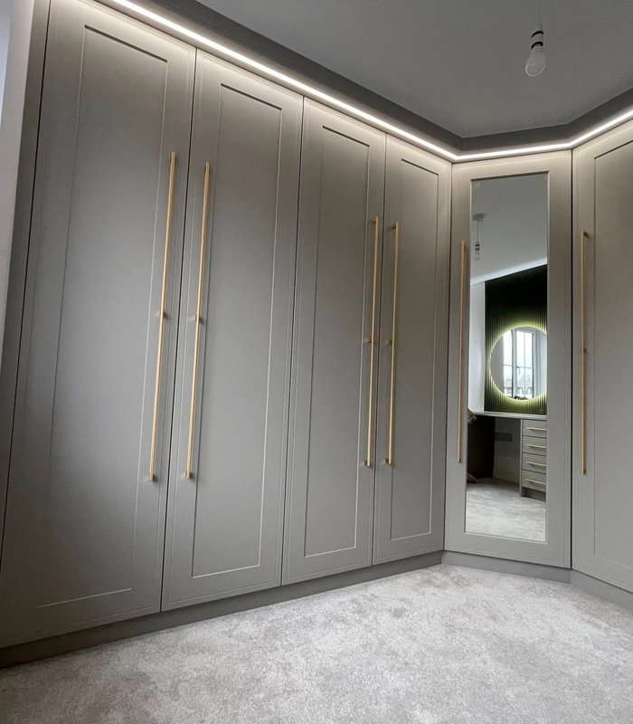 Floor-to-ceiling grey wardrobes with a mirrored corner and LED lighting