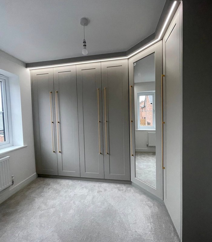 Grey fitted wardrobes beside a window with integrated lighting