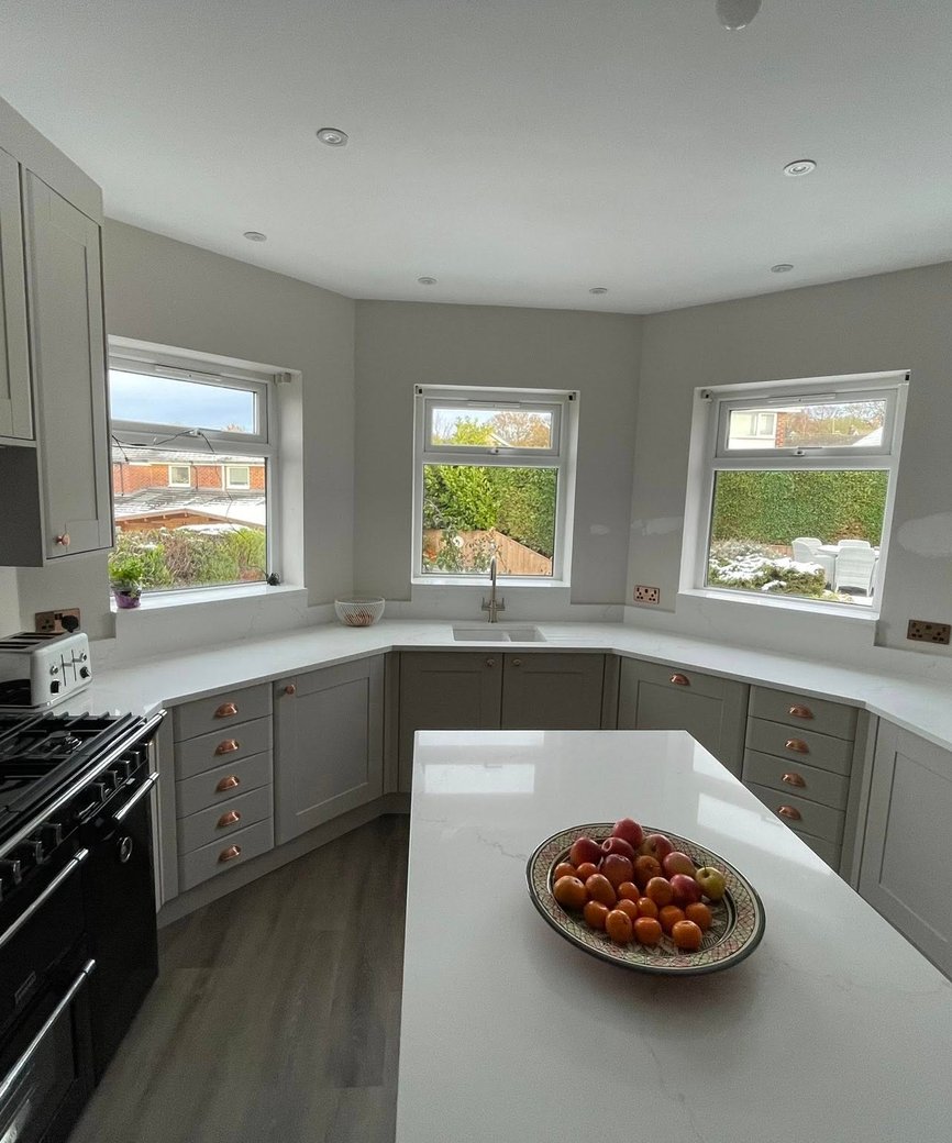 Grey shaker fitted kitchen with copper handles and curved cabinetry