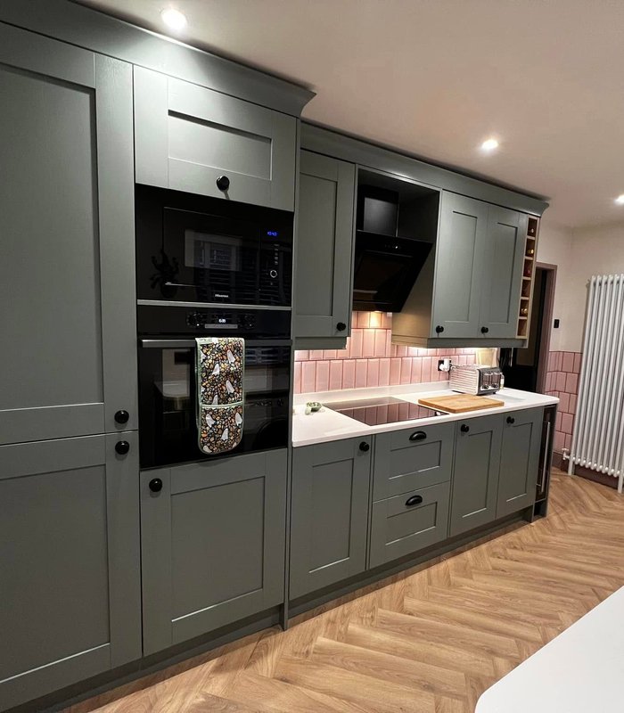 Charcoal kitchen with a pink tiled splashback and fitted appliances