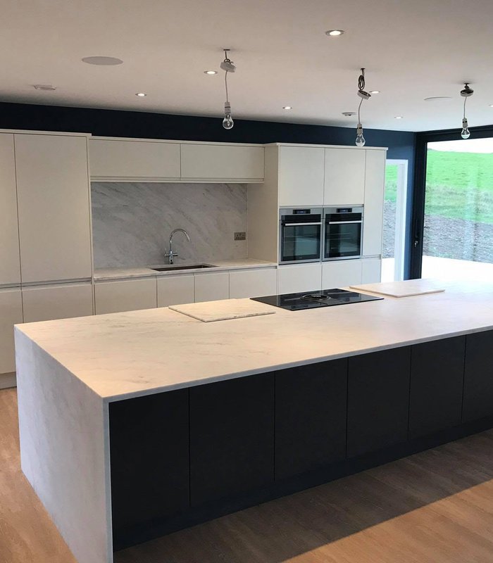 Handleless light-grey kitchen with a black island and garden doors