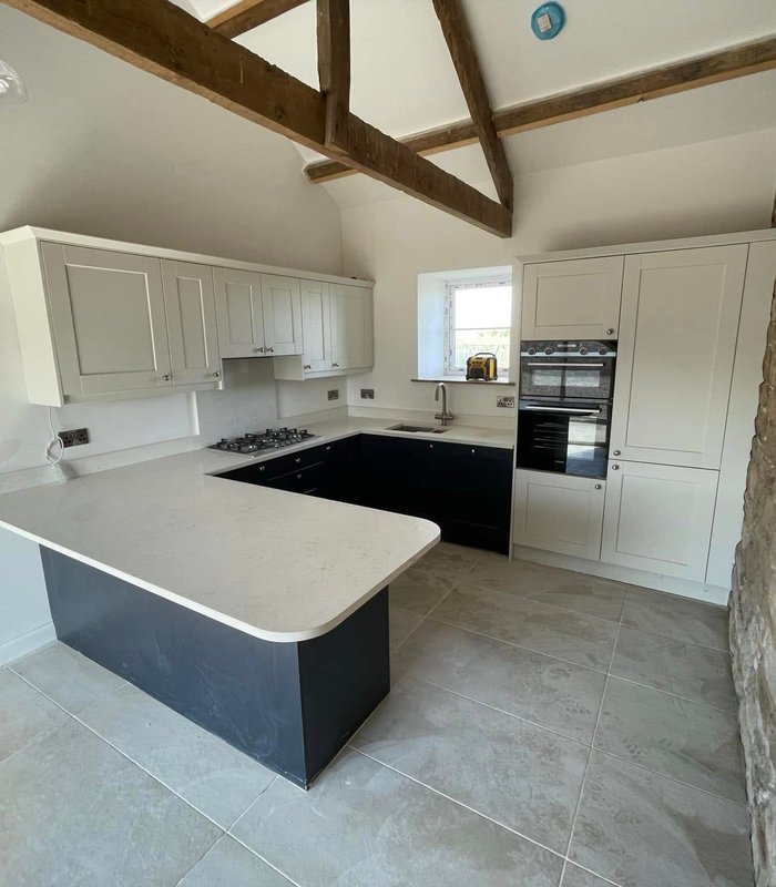 White and charcoal kitchen with an island beside a stone feature wall