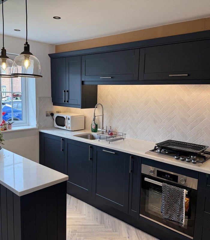 Dark blue fitted kitchen with marble-effect splashback and worktops