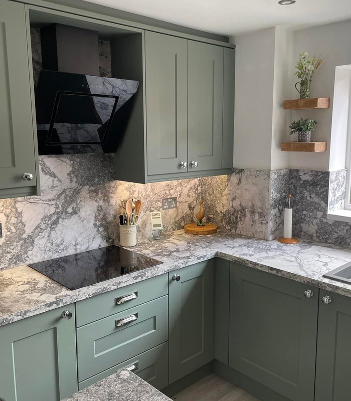 Sage green corner kitchen with marble-effect worktops