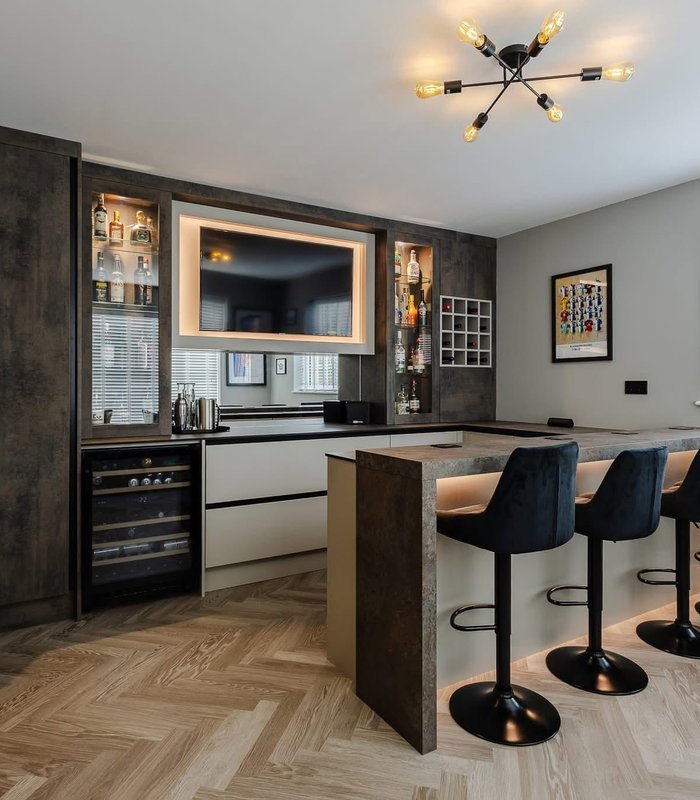 Dark fitted home bar with a television and display cabinets