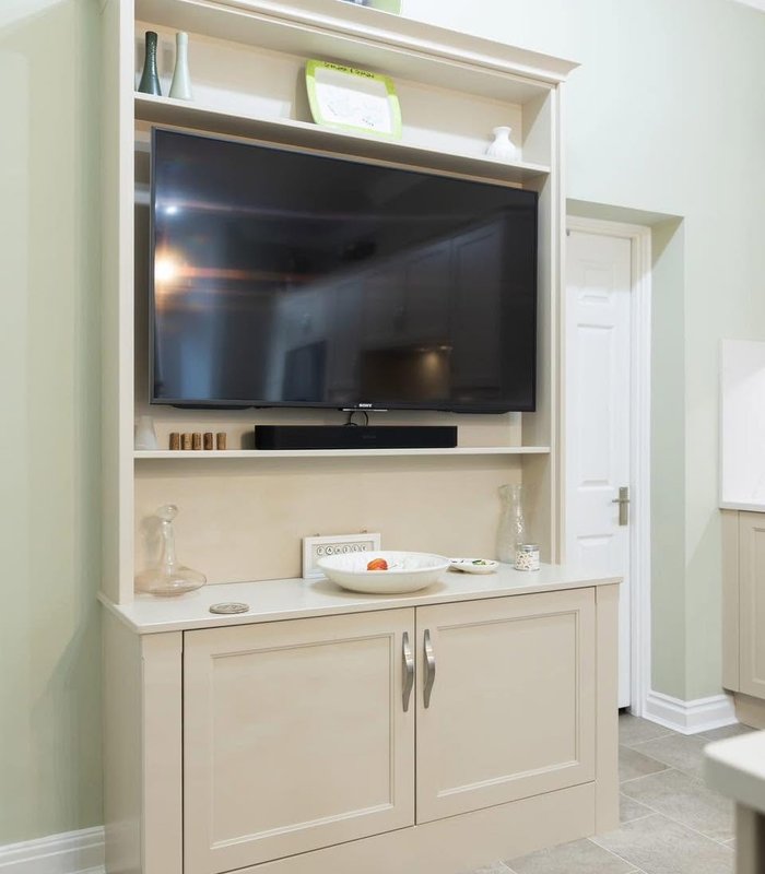 Traditional light-coloured fitted TV cabinet with display shelving