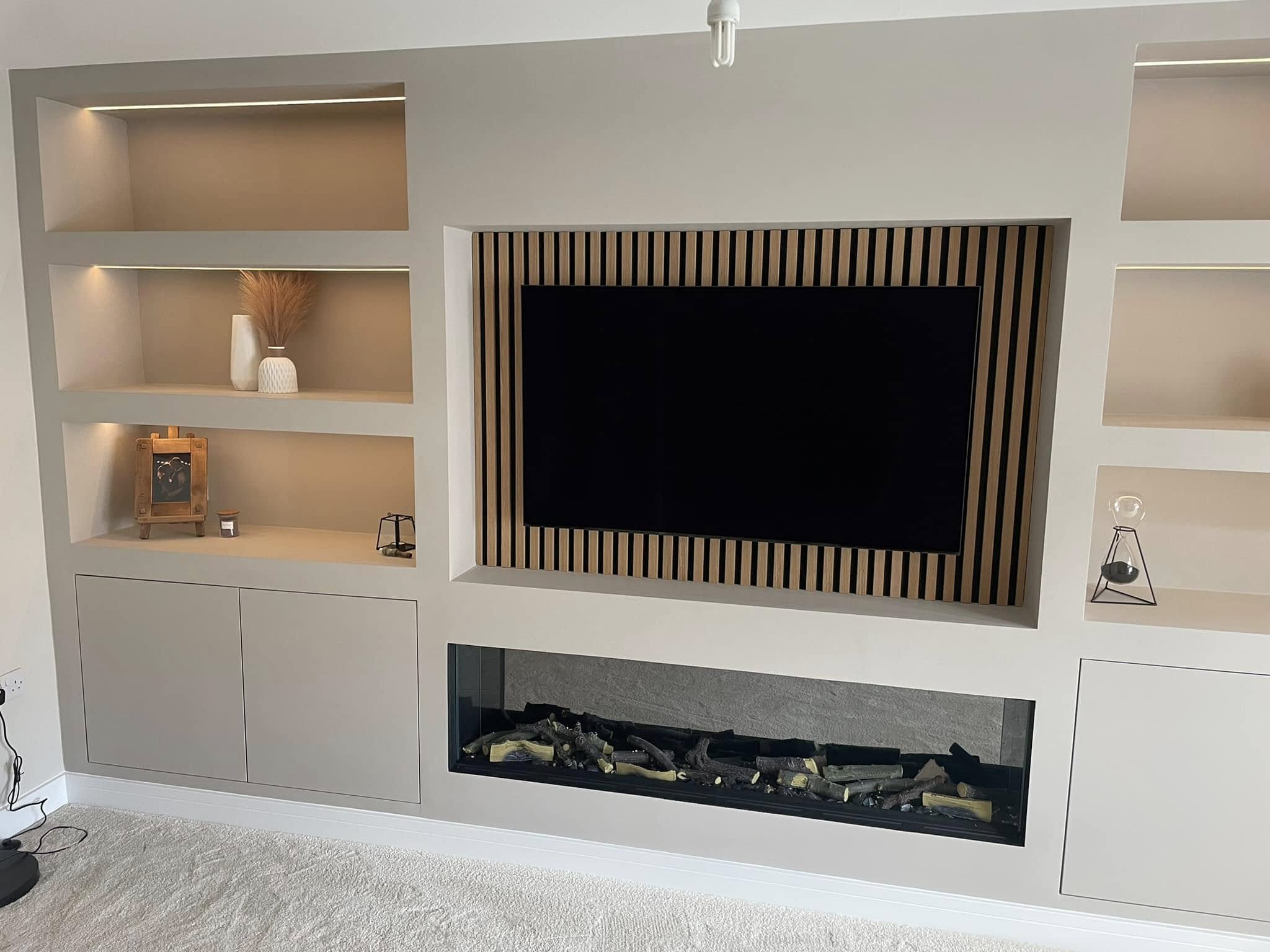 White fitted media wall with display shelving and a fireplace